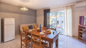 A dining area with a wooden table set for breakfast, a sofa, and a refrigerator. - Domaine Bollaccia - Casa Bodri (Monticello)