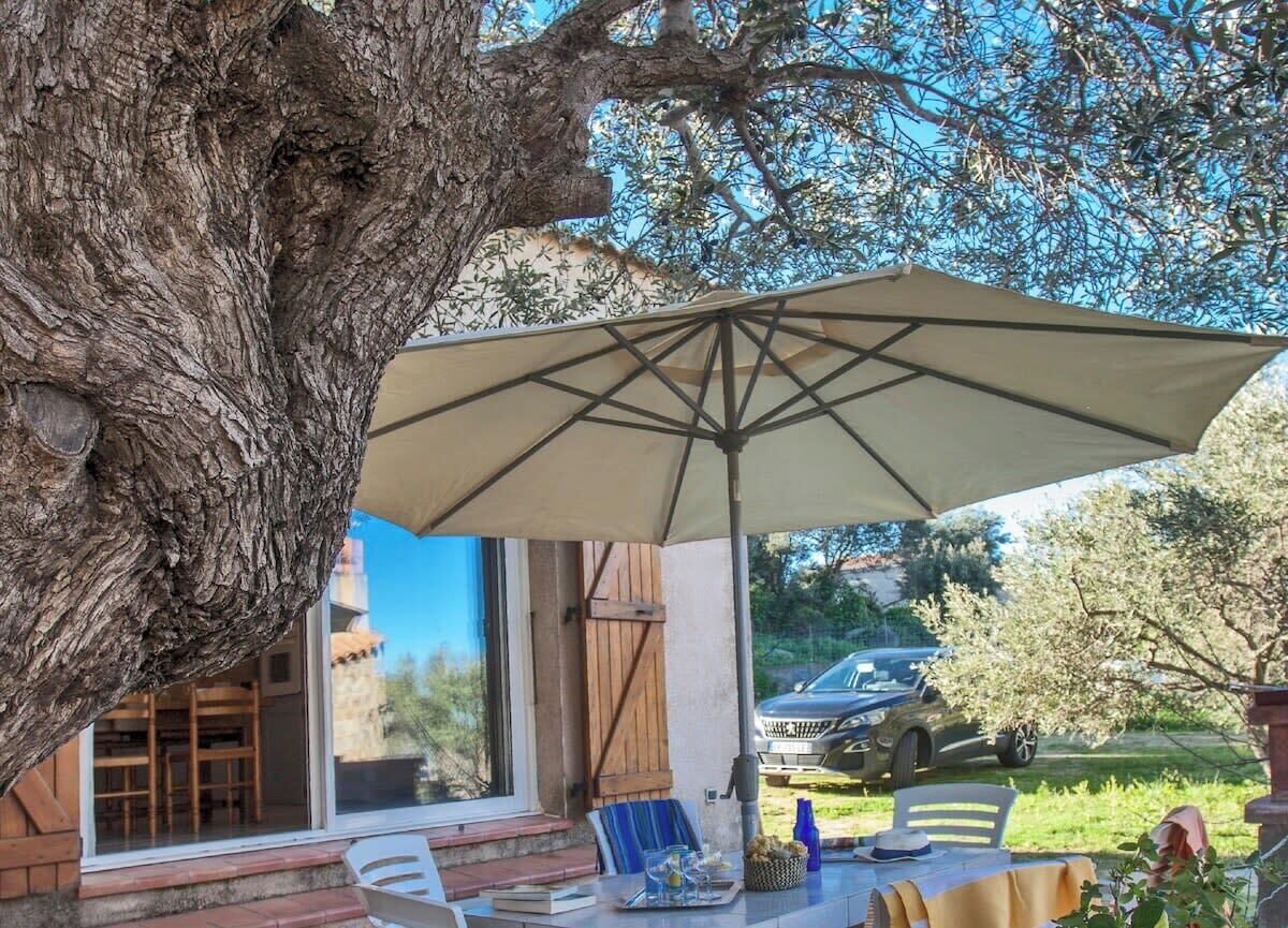 An outdoor patio area with a large umbrella, a table, and chairs.