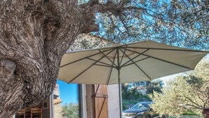 An outdoor patio area with a large umbrella, a table, and chairs. - Domaine Bollaccia - Casa Bodri (Monticello)