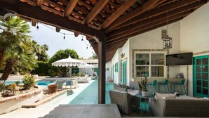 A covered outdoor area with a pool, wicker furniture, and a dining table. - Spacious 4BR Historic Spanish Estate/Pool,Casita & Mountain Views/Old Las Palmas (Palm Springs)