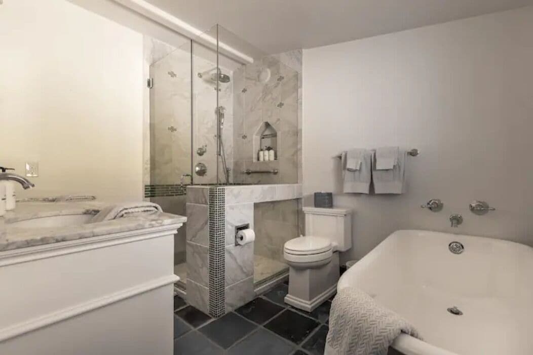 A modern bathroom with a glass-enclosed shower, a toilet, and a bathtub.