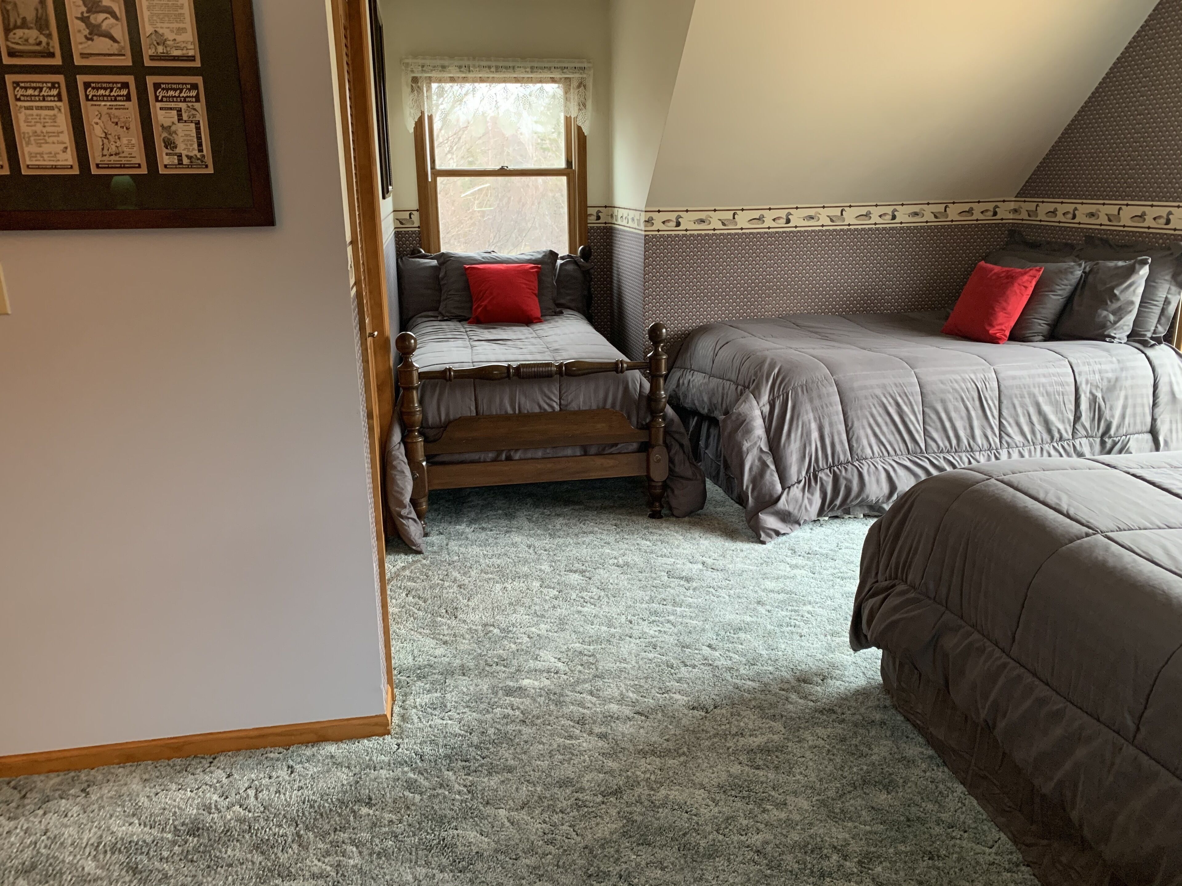 A bedroom with a loft bed, a lower bunk bed, and a small chair.