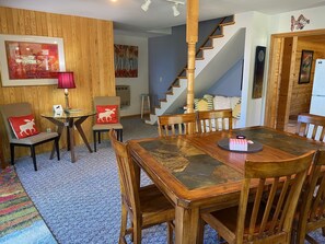 A dining area with a wooden table and chairs, a red moose pillow, and a painting on the wall. - Perfect Grand Marais Get-Away! Pictured Rocks, snowmobile trails, beaches, etc (Grand Marais)