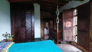 A bedroom with a bed, wooden doors, a staircase, and a hanging light fixture.