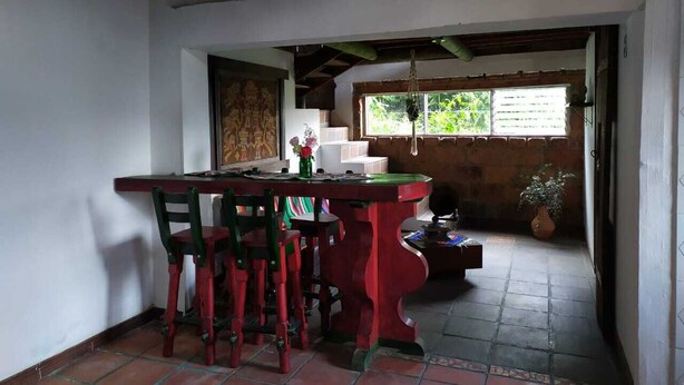 A dining area with a wooden table and chairs, a ceiling fan, and a window with a view of greenery.