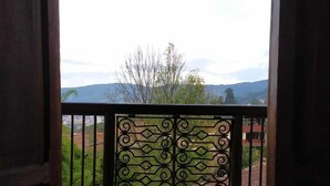 A balcony with a green mat, a metal railing, and a view of a mountainous landscape.