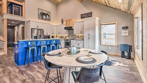 Una cocina amplia con una isla central, taburetes de bar y una mesa de comedor lista para cuatro.