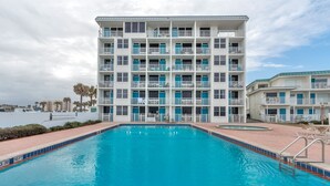 Un hotel de varios pisos con piscina al frente.