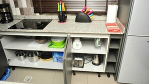 Eine Küche mit eingebautem Herd, verschiedenen Kochutensilien, einer Kaffeemaschine und einem Kühlschrank.
