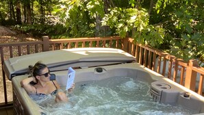Un jacuzzi con muelle de madera y barandilla metálica, rodeado de árboles.