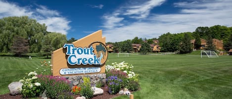 Naamplaatje voor Trout Creek Condominium Resort & Vacation Rentals, met een verzorgd gazon en een voetbalveld.