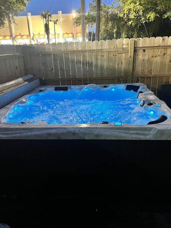 A hot tub with a wooden fence in the background.