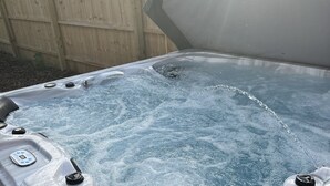 Un bain à remous doté d’un panneau de commande et, en arrière-plan, une clôture en bois.