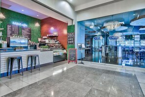 A modern coffee shop with a green wall, a bar area, and a seating section with stools.