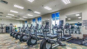 Una palestra con diverse tapis roulant ed ellittiche, ampie finestre e un tappeto a motivi.