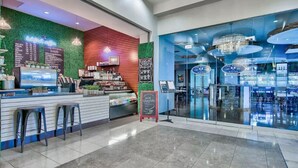 Un caffè moderno con una parete verde, un bancone e una zona con sgabelli.