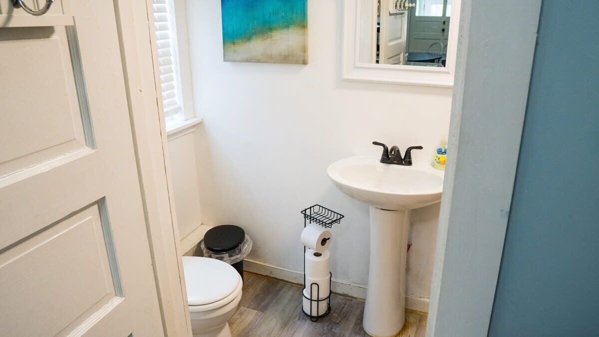 A small, clean bathroom with a toilet, sink, and a trash bin.