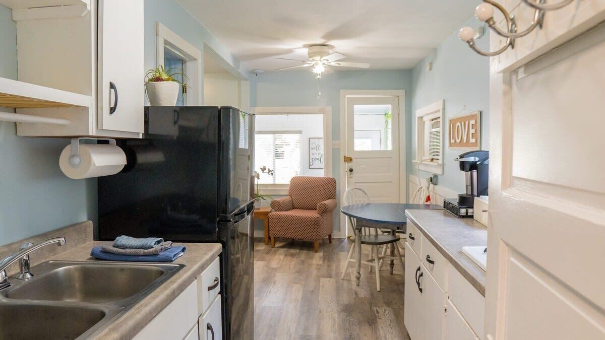 A compact kitchen with a refrigerator, sink, and a dining area with a chair and table.