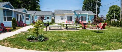A row of small, single-story cabins with outdoor seating areas and a well-maintained lawn.