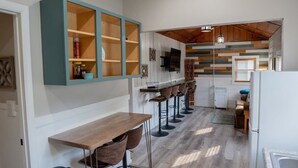 Et køkken med en træbar, et hvidt køleskab og et træloft.