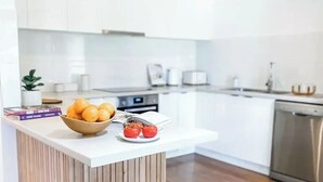A modern kitchen with white cabinets, a wooden countertop, and a bowl of fruit. - Stylish duplex in Prime Location! (Wagga Wagga)