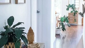 A room with a wooden floor, a white door, a small table with a Buddha statue and a plant, and a mirror on the wall. - Stylish duplex in Prime Location! (Wagga Wagga)