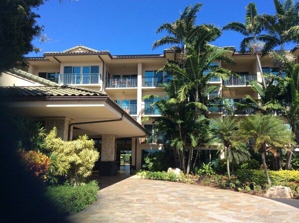 Ein mehrstöckiges Hotel mit Innenhof, Palmen und einem gefliesten Weg.