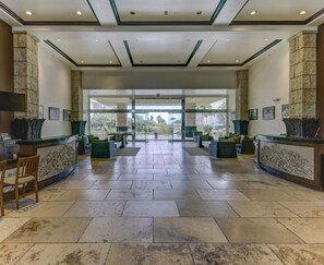 Eine großzügige Lobby mit Steinboden, einer Rezeption und Sitzbereichen.