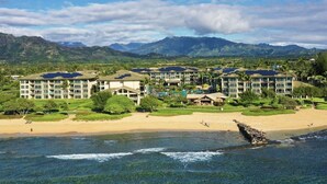 A coastal hotel with multiple buildings, a sandy beach, and mountains in the background. - 2 Bedroom 3 bath in Waipouli Deluxe oceanfront condominium Resort (Kapaa)