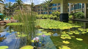 A hotel courtyard with a pond, water lilies, and palm trees. - 2 Bedroom 3 bath in Waipouli Deluxe oceanfront condominium Resort (Kapaa)