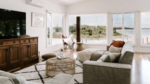 Un salon spacieux doté d’un grand téléviseur, de sièges confortables et offrant une vue sur l’extérieur.