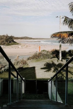 Un escalier menant à une plage d’où l’on a une vue dégagée sur le rivage.