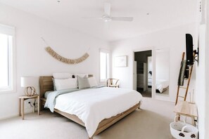 A bedroom with a bed, a ceiling fan, a lamp, a chair, and a wardrobe. - Ocean Essence (Currarong)