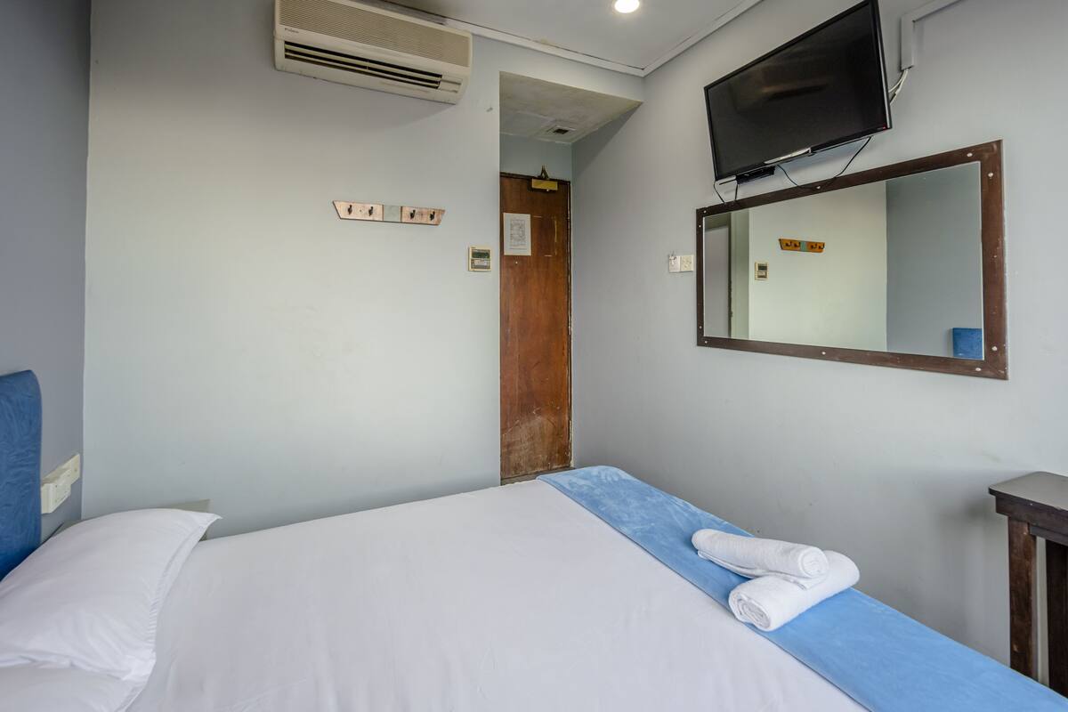 Ein Hotelzimmer mit Bett, Fernseher, Spiegel und Klimaanlage.