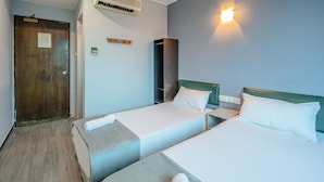 A hotel room with two single beds, a wooden door, a wardrobe, and a wall-mounted light fixture. - K Hotel 1515 (Singapore)