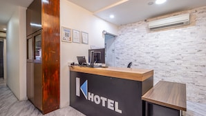 A hotel reception desk with a modern design, featuring a logo, a computer, and a small table. - K Hotel 1515 (Singapore)