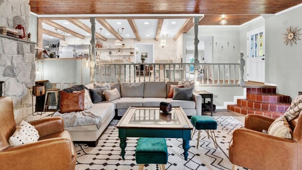 Un salon spacieux, doté d’un grand canapé, d’une table basse et d’un escalier menant à un niveau supérieur.