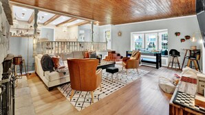 Un vaste espace de vie doté d’un plafond en bois, d’un canapé, de fauteuils, d’une table basse et d’un jeu d’échecs.