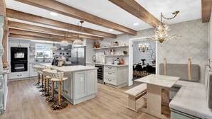 Une cuisine moderne dotée d’un îlot central, de tabourets de bar et d’un coin repas avec une banquette.