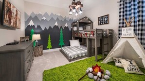 Un dormitorio con cama, literas, una tienda de campaña, una lámpara, un cuadro y un mural en la pared.