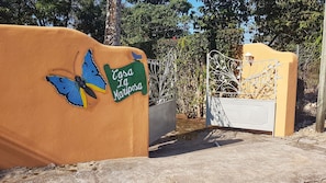 Enter Casa La Mariposa through a beautifully designed gate, surrounded by lush greenery and trees.