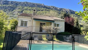 Ein Haus mit Schwimmbecken, umgeben von einer Holzterrasse und einem eingezäunten Bereich.