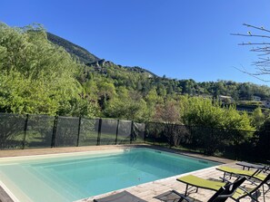 A rectangular swimming pool with a wooden deck and green lounge chairs. - Cozy villa with a large garden, private pool, huge trampoline, and swing (SAHUNE)