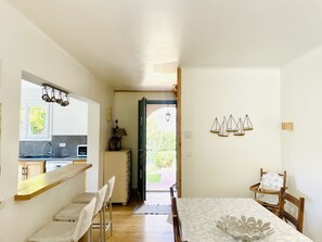 A dining area with a table, chairs, and a view into the kitchen. - Cosy villa with large garden, private pool, giant trampoline, swing (SAHUNE)