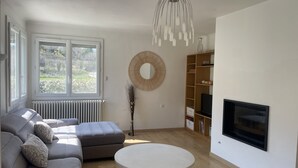 Ein Wohnzimmer mit einer Couch, einem runden Spiegel, einem Kamin und einem Bücherregal.