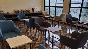 A modern cafe with a checkered floor, various seating options including blue and brown chairs, and a large window with artwork. - KingKabba Guest House Wonosobo (Wonosobo)