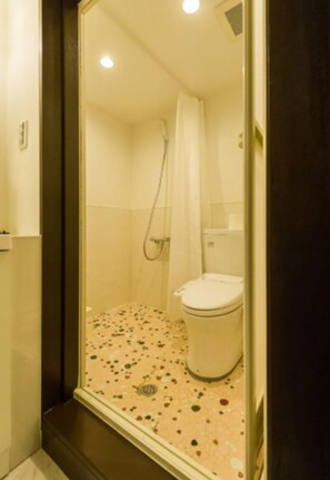 A small bathroom with a shower, toilet, and a tiled floor.