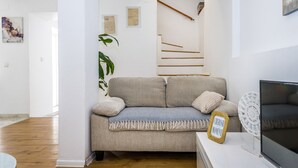 Una sala de estar con un sofá color beige, un televisor y un letrero decorativo.