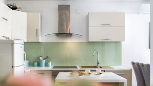 Una cocina moderna con armarios blancos, una campana extractora de acero inoxidable, un salpicadero de vidrio y una encimera blanca.