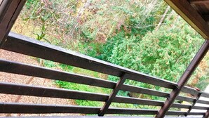 A covered outdoor area with a concrete floor and metal railings, overlooking a forested area. - Pension Jägerschenke (Luhe-Wildenau)